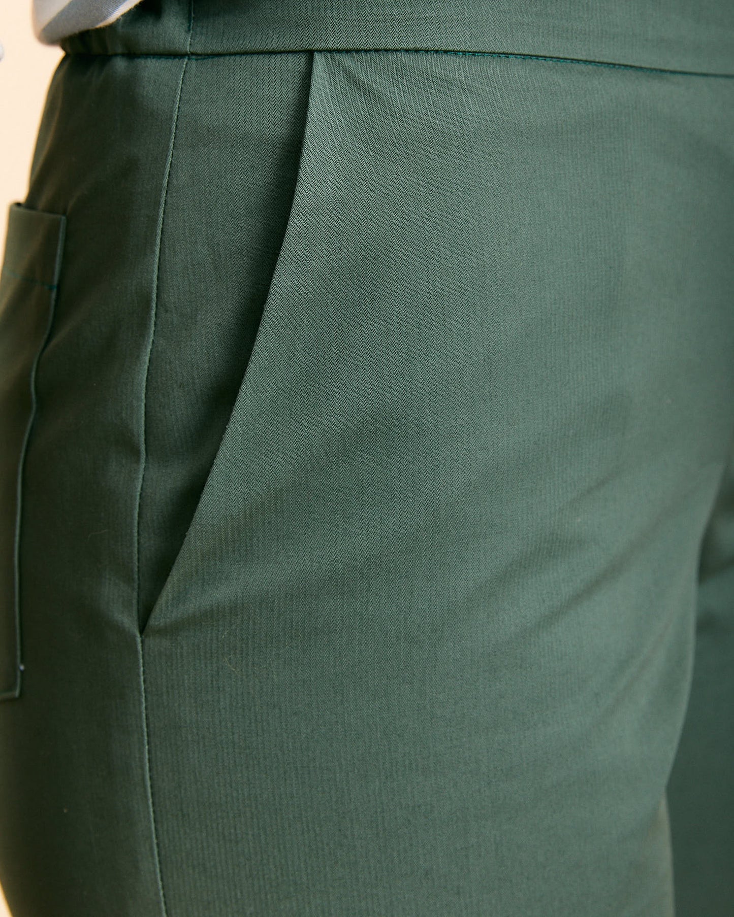Un pantalone con uno stile più fitted realizzato in cotone 100% color verde timo.  Il pantalone Ninfa ha una vestibilità regolare, che segue il corpo nella zona del bacino e scende dritto sulla gamba. Il cinturino ha elastico sul retro e una cerniera sul fianco per adattarsi al meglio alla tua taglia.  Oltre alle tasche alla francese sul davanti ha due tasche applicate sul dietro.