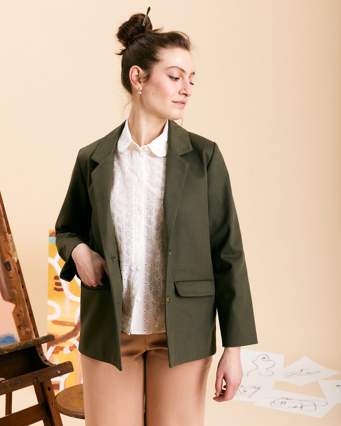 Un blazer realizzato in 100% cotone color verde sottobosco.  Il blazer Mimi rispetta la linea asciutta e maschile del capo, una giacca leggermente sfiancata con due tasche con pattina e due bottoni sul davanti.